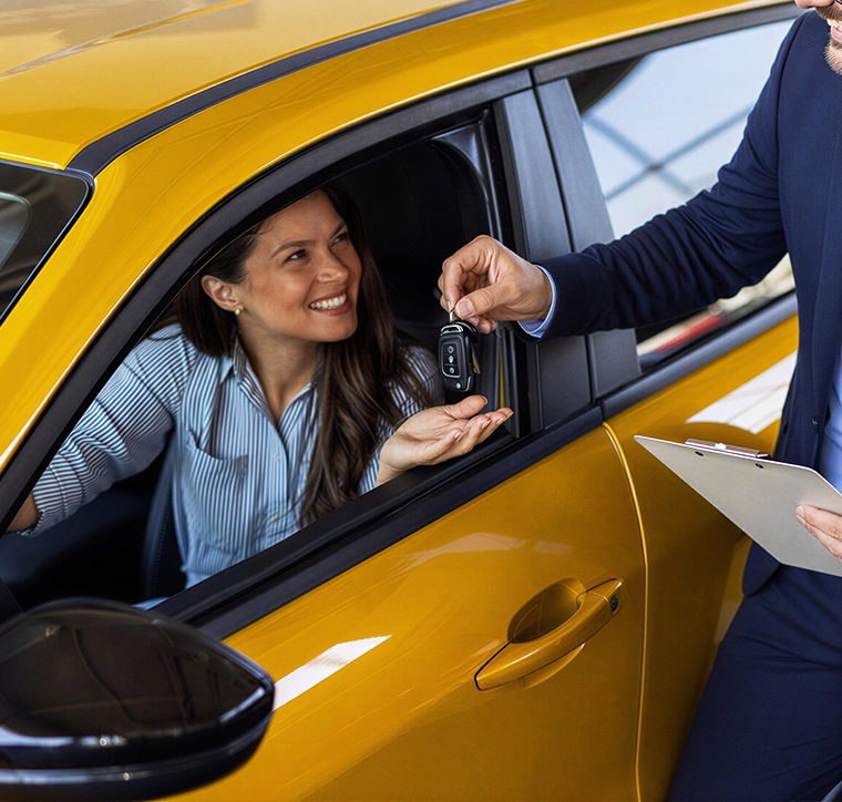 A professional agent in a suit handing over car keys to a smiling female driver in a yellow taxi, representing excellent customer service and vehicle delivery.