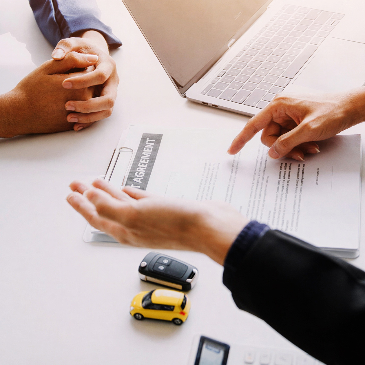 Professionals discussing a "Fleet Agreement" on a clipboard next to cars.